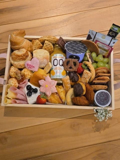 Cesta de café da manhã com pães, frutas, suco e doces, vista de cima.