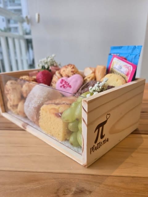 Caixa de madeira da Platteria com pães, frutas, flores e pequenos presentes gastronômicos.